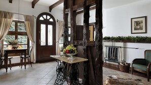 A dining area with a wooden table, chairs, and a fruit bowl. There is a large wooden beam structure in the center, and a green chair is visible in the background. - Oliwa Park Residence (Gdansk)