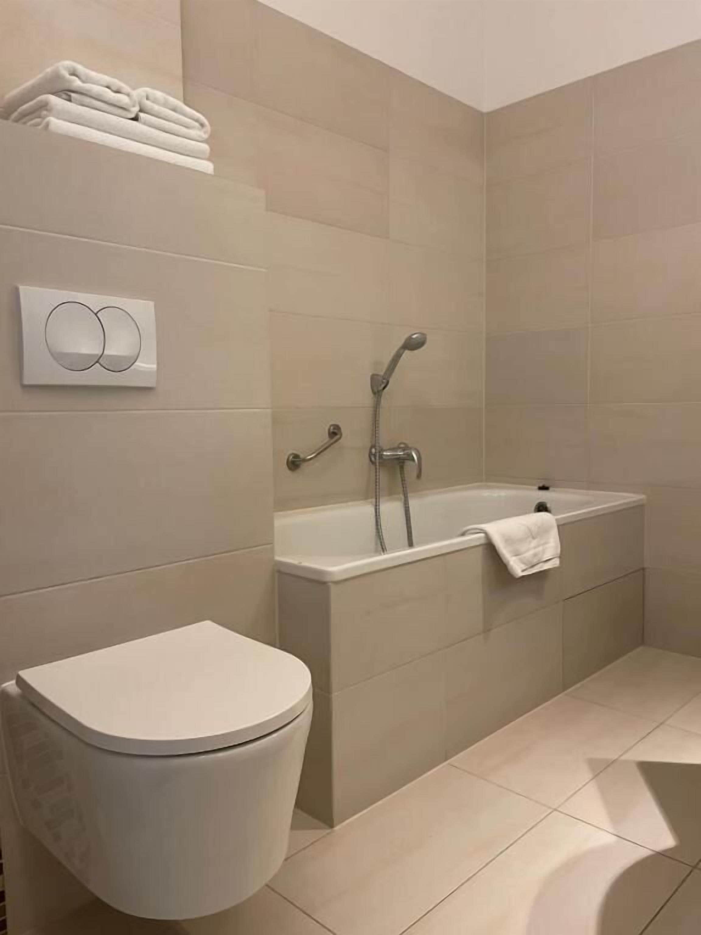 A modern bathroom with a toilet, a bathtub, and a shower.