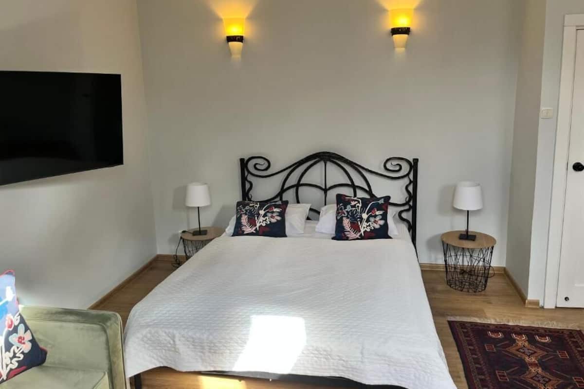 A neatly made bed with a white duvet, two wall-mounted lamps, and a decorative pillow.