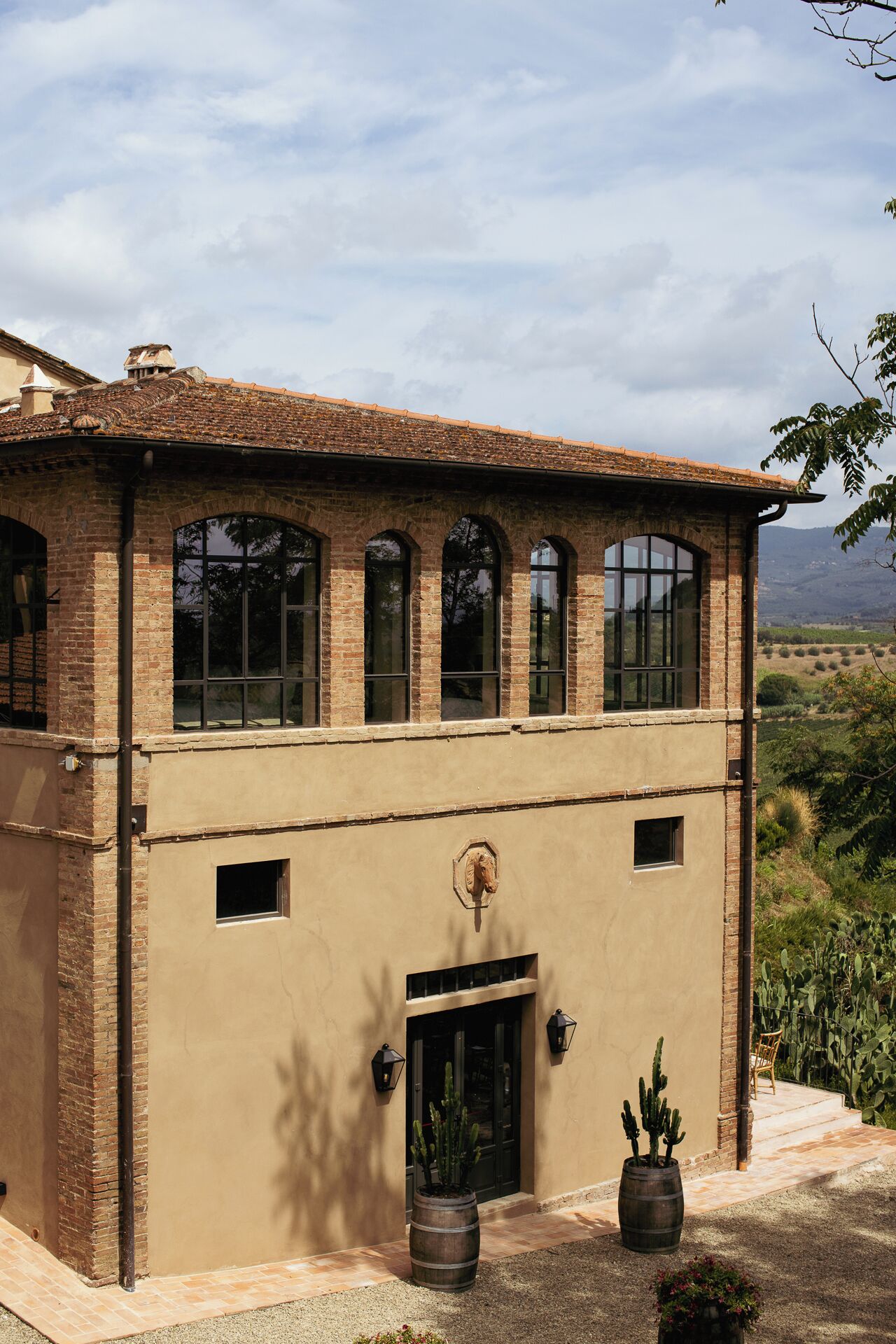 Um edifício de dois andares com fachada de tijolos, janelas em arco grandes e telhado plano.