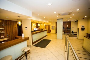 A hotel lobby with a reception desk, a bar area, and a seating area. - Hotel Geblergasse (Vienna)