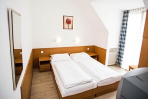 A bedroom with a wooden bed, bedside tables, a mirror, a radiator, and a window with curtains. - Hotel Geblergasse (Vienna)