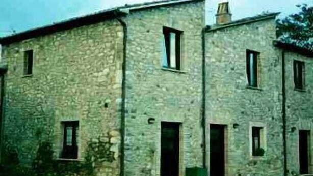 A stone building with multiple windows and doors, likely a residential or small commercial structure. - Barberani (Baschi)
