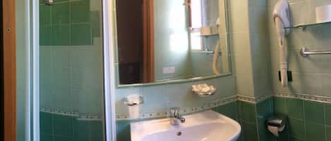 A bathroom with a white sink, a mirror, a towel rack, and a hairdryer on the wall.