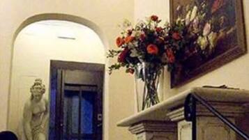 Un corridoio con una statua, un vaso di fiori e un quadro appeso al muro.