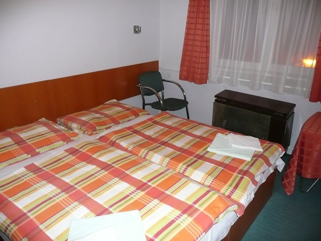 Una habitación de hotel con una cama doble, una silla, una mesita y un televisor.