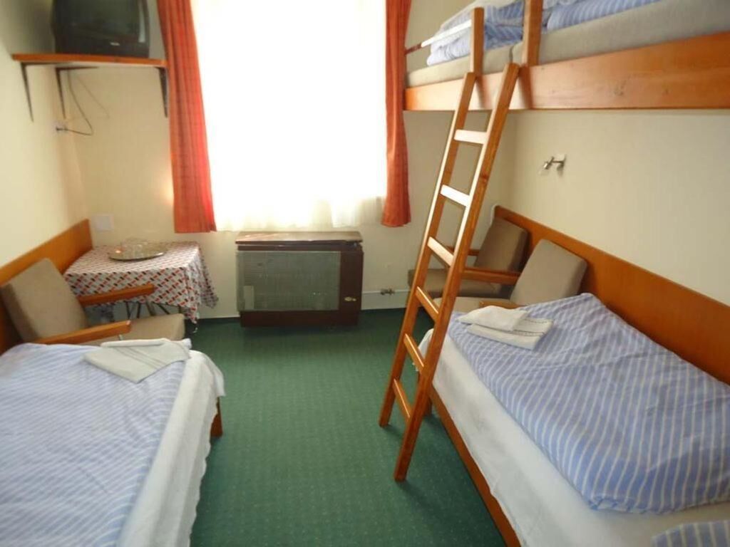 Een kamer met stapelbedden, een klein tafeltje en een televisie, en een trap.