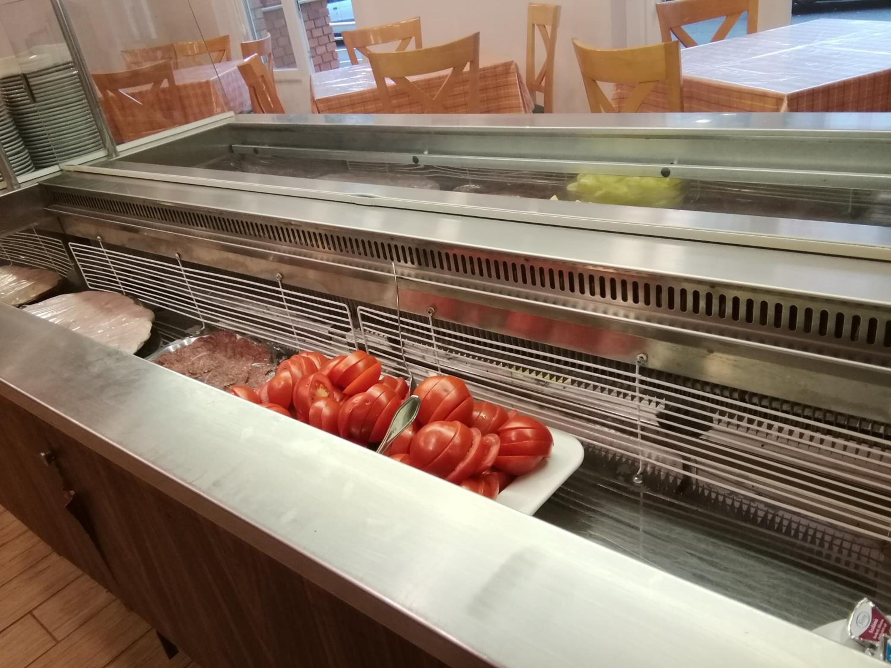 A buffet area with various food items, including sliced tomatoes and covered dishes.