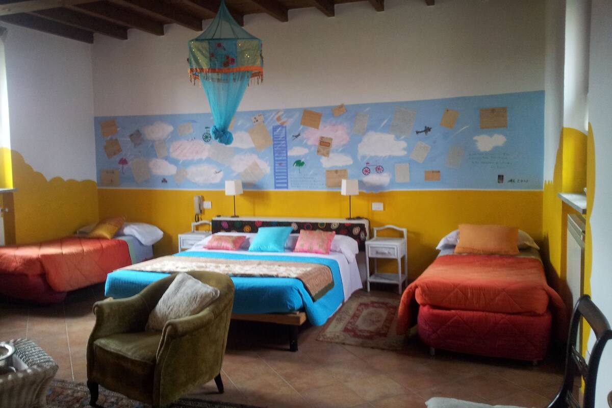 A room with two beds, a chair, and a wall mural.