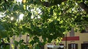 A courtyard with a swing set, outdoor seating, and a building with a yellow facade and red trim. - Il Pioppo e la Fonte (Castello d'Agogna)