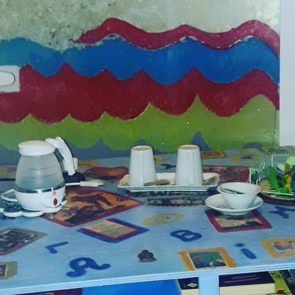 Una mesa con cafetera, tazas y un plato de comida.