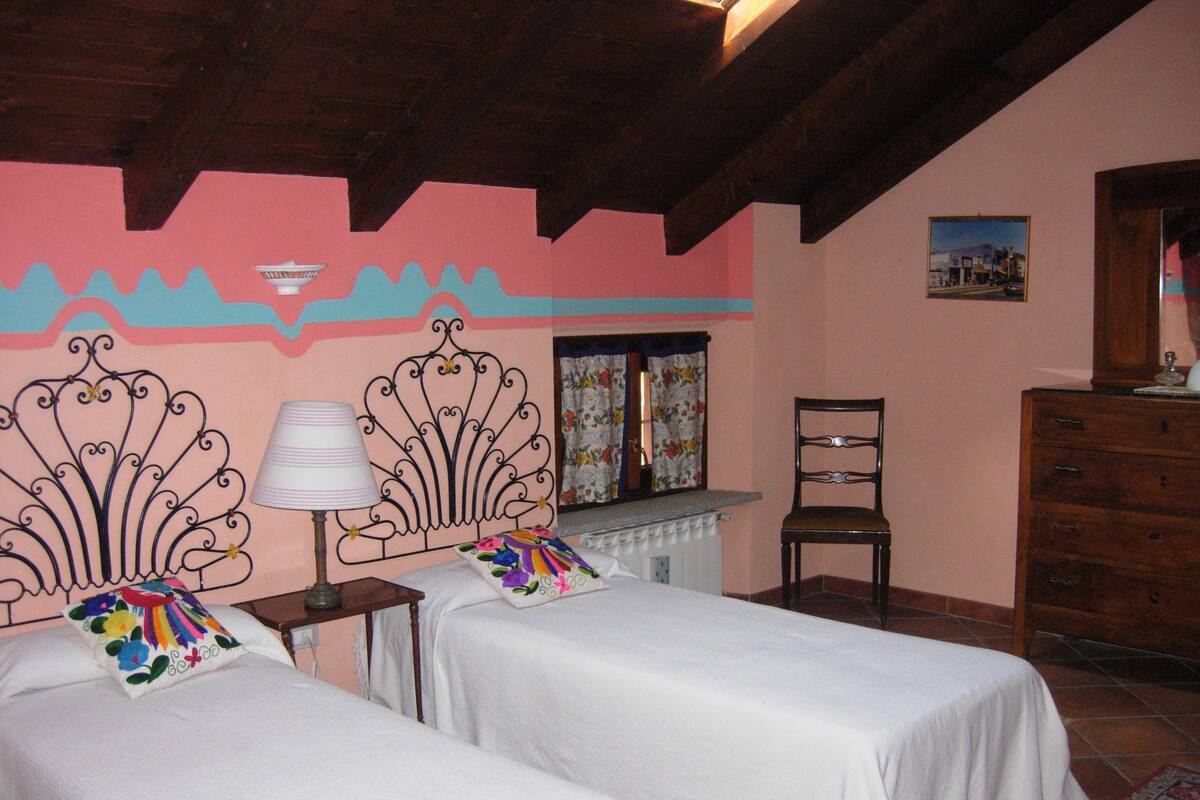 A bedroom with two beds, a chair, a dresser, and a window with curtains.
