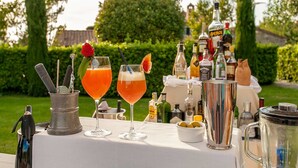 Une table dressée à l’extérieur, avec deux cocktails, un pichet en métal et diverses bouteilles en arrière-plan.