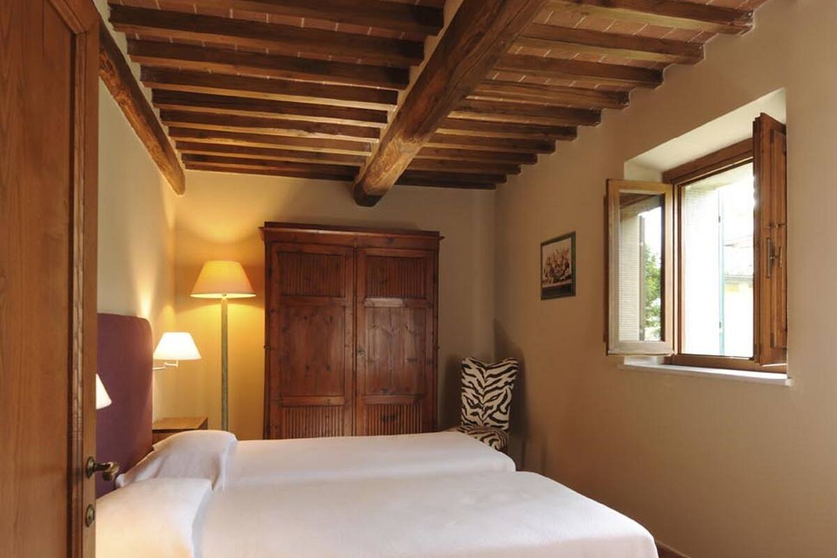 Een slaapkamer met een bed, een houten garderobe en een raam met openslaande luiken.