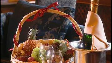 A wicker basket filled with fruits and grapes, a bottle of champagne, and two champagne flutes on a table.
