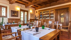 Un restaurant avec des tables et des chaises en bois, un meuble à vin et des œuvres d’art encadrées accrochées aux murs.