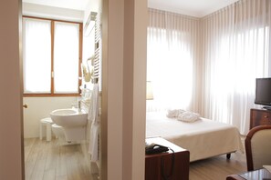 Une chambre d’hôtel avec salle de bain, un lit, une télévision et un bureau.