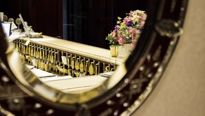 A close-up of a bar with a mirror reflecting a row of bottles and a vase with flowers. - Hotel Bristol (Milan)