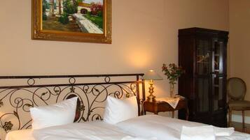 Ein Hotelzimmer mit einem Bett, einem Bild an der Wand, einer Lampe, einer Vase mit Blumen und einem Holzkabinett.