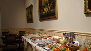 Una mesa de buffet con diferentes alimentos y un área de comedor con sillas y una mesa.