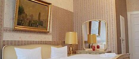 A hotel room with a bed, a nightstand, a lamp, a mirror, and a painting on the wall.