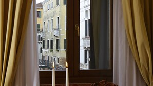 Una mesa dispuesta con una bandeja, vasos y velas, mostrando vistas de edificios a través de una ventana.