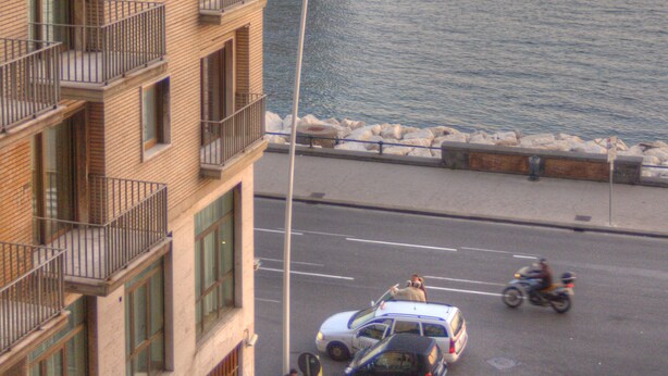 Un edificio de varios pisos con balcones que dan a una carretera costera.