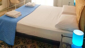 Habitación de hotel con cama, escritorio, silla, televisor y ventana con cortinas.
