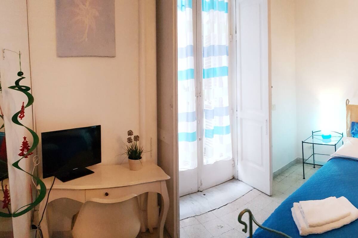 A hotel room with a bed, a TV, a desk, and a sofa.