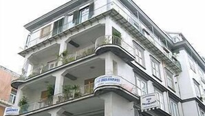 Un edificio de varios pisos con balcones, una cafetería y un letrero que indica un restaurante.