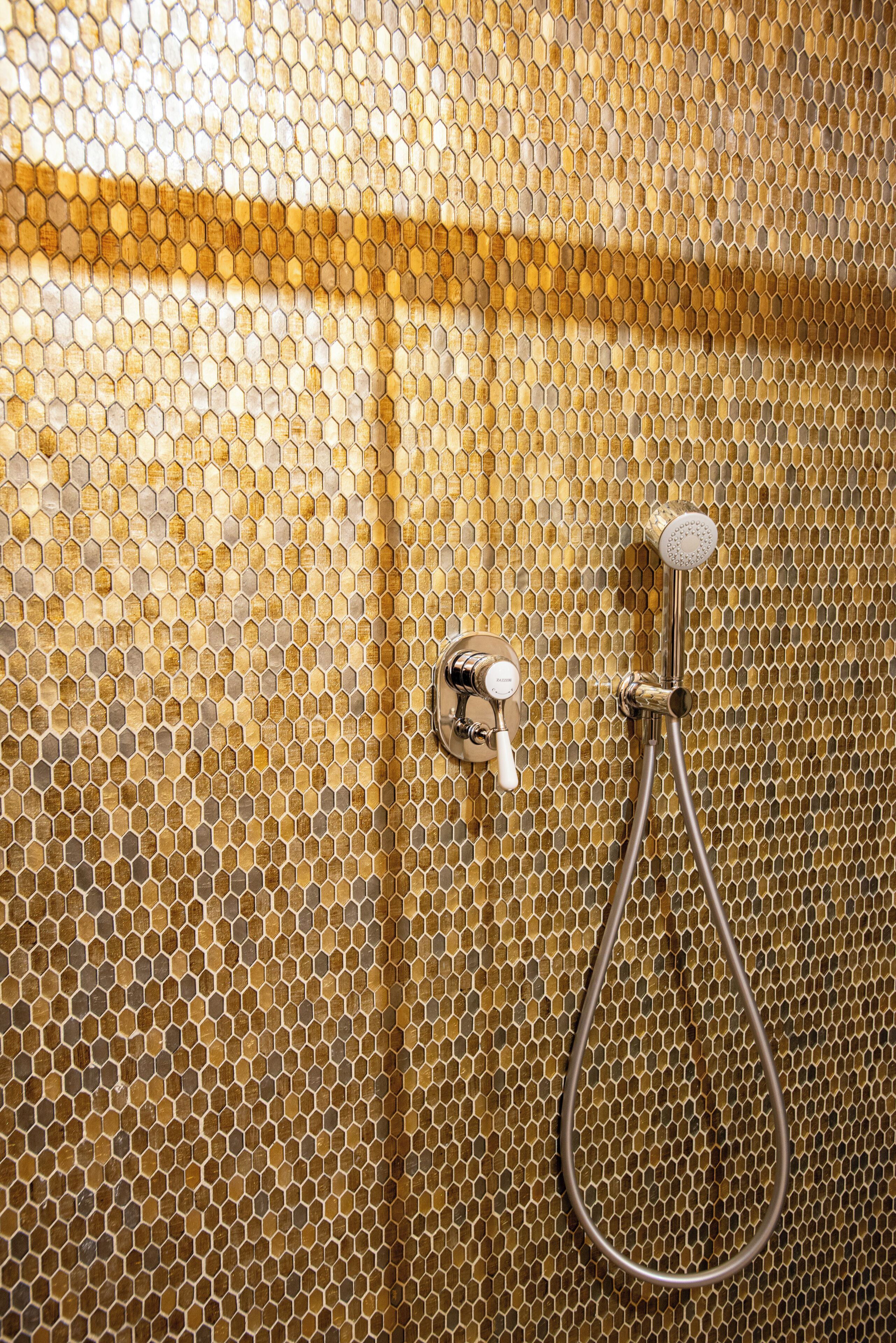 Un baño con una pared de diseño tipo panal y una ducha.