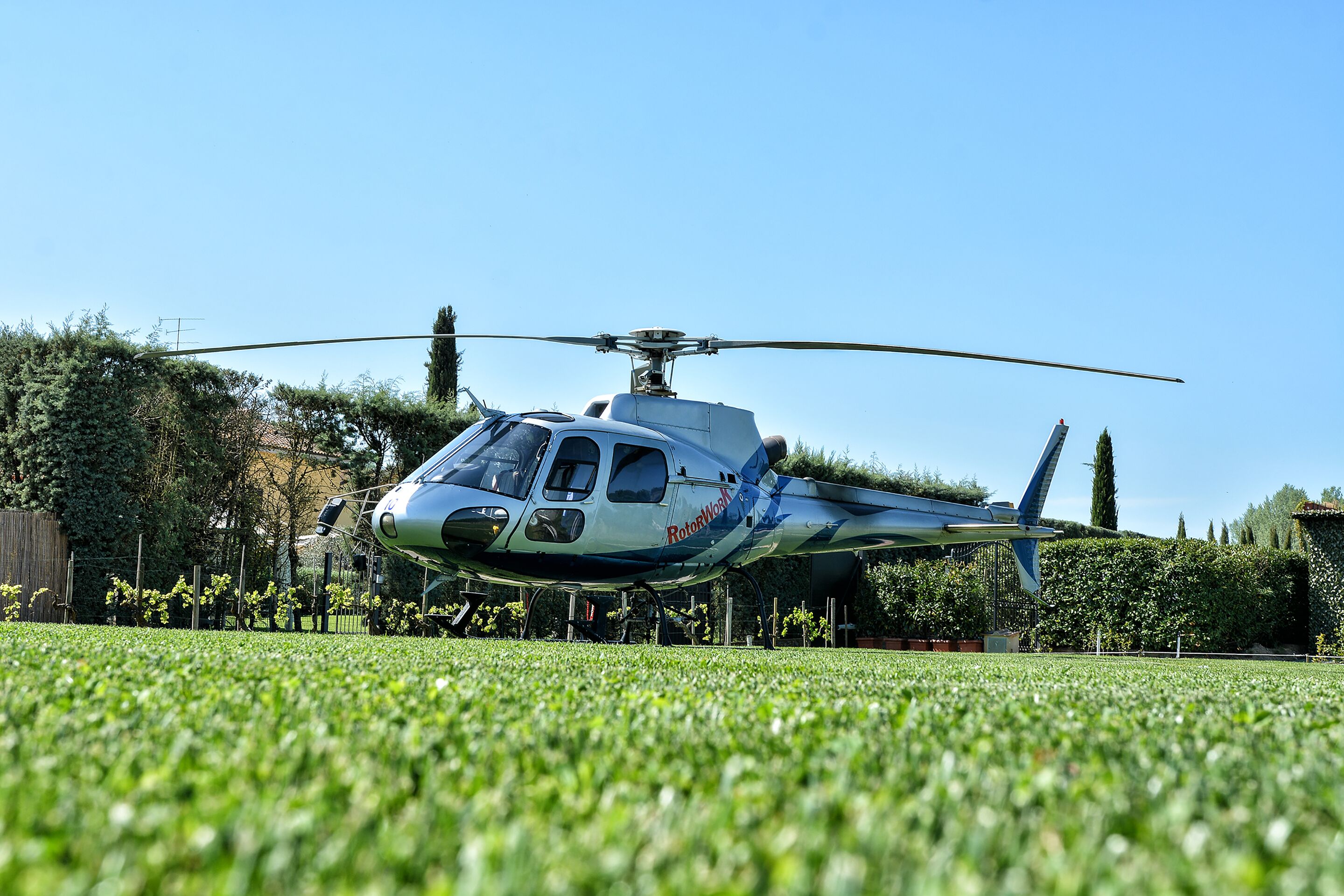 A helicopter parked on a grassy field with a clear blue sky in the background.