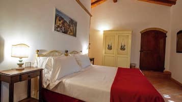 Un dormitorio con cama, mesita de noche, lámpara, armario y un cuadro en la pared.