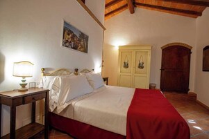 Un dormitorio con cama, mesita de noche, lámpara, armario y un cuadro en la pared.