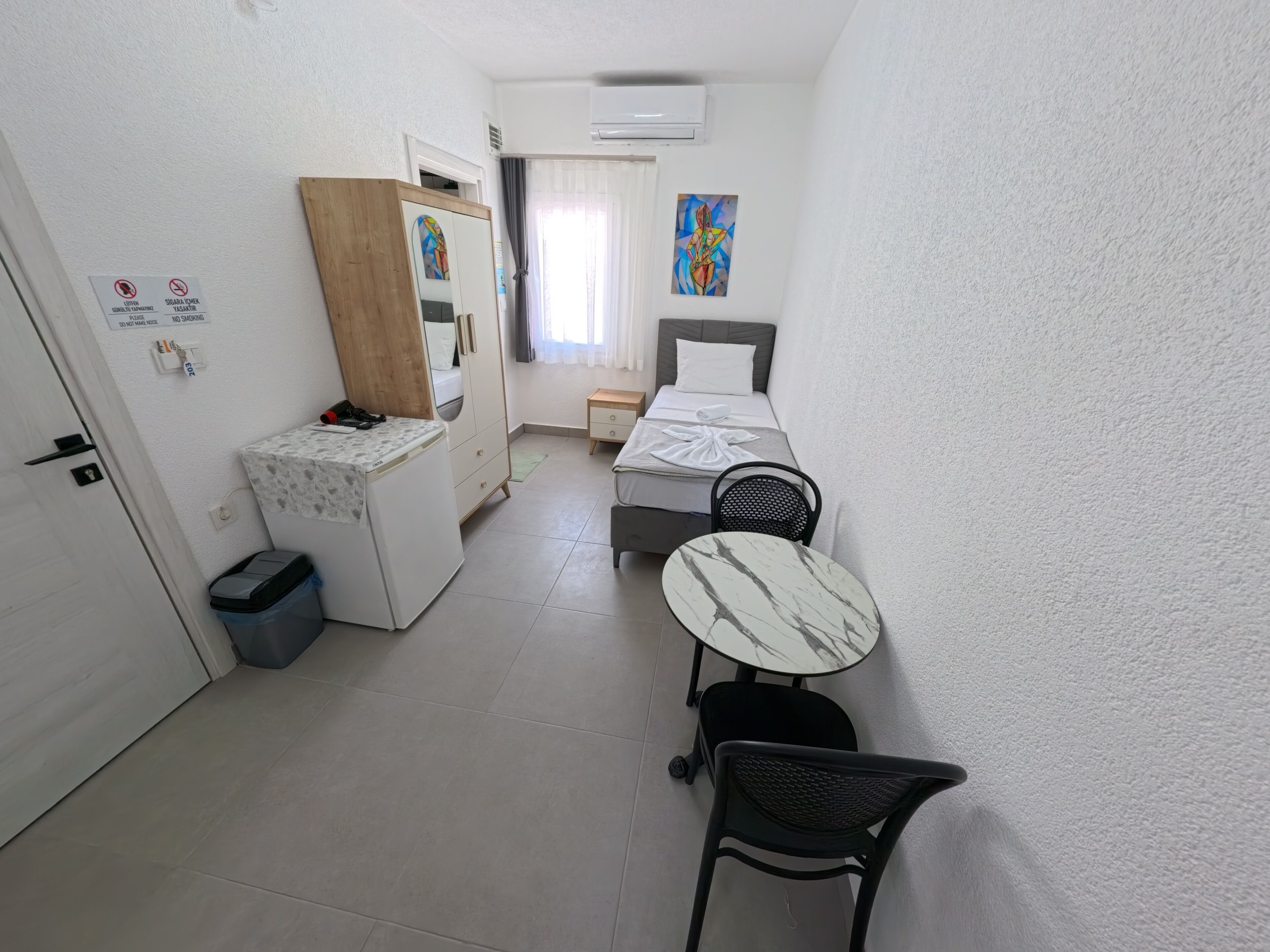 A small, clean room with a bed, a desk, a chair, and a small table.
