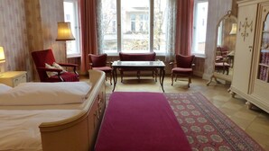 A hotel room with two beds, a dining table, and a large window with curtains. - Hotel-Pension Funk (Berlin)