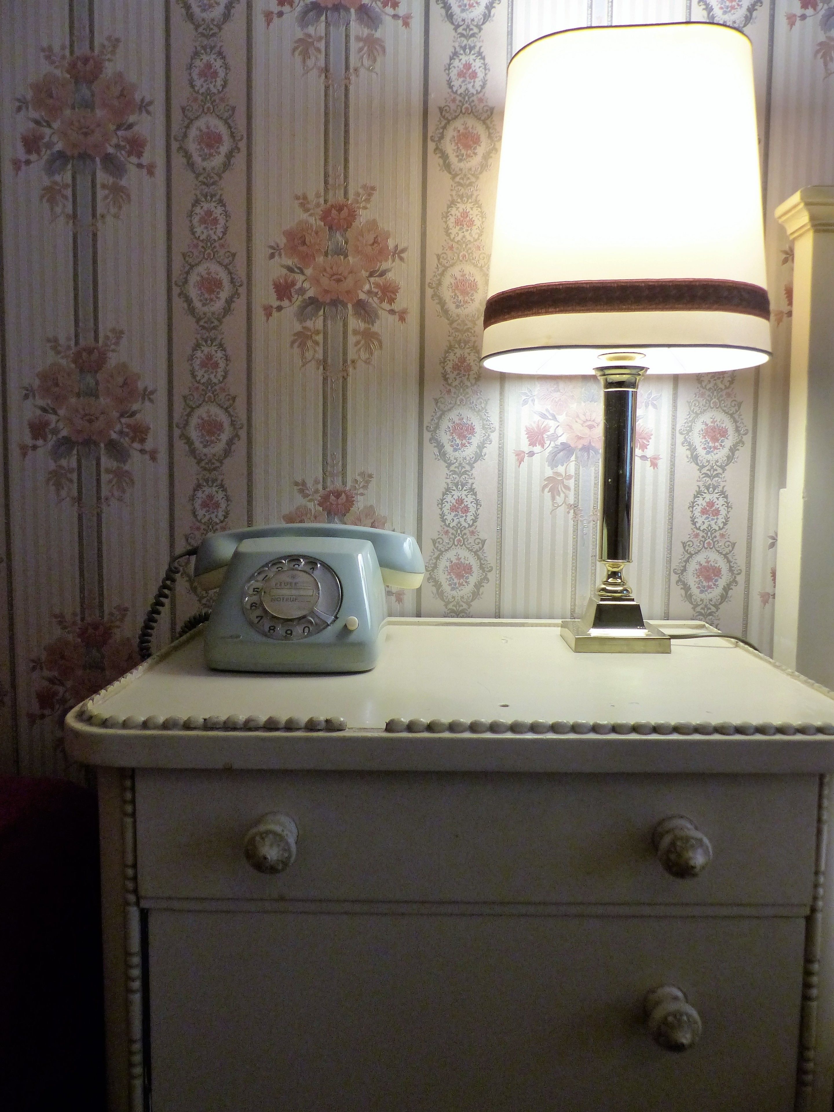 A vintage-style nightstand with a telephone and a lamp.
