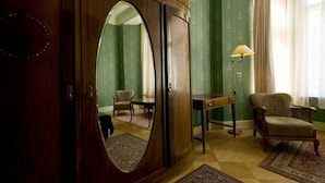 A room with a large wooden wardrobe, a mirror, a table, two chairs, and a lamp. - Hotel-Pension Funk (Berlin)