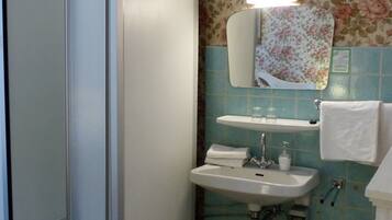 A bathroom with a shower, sink, and mirror.