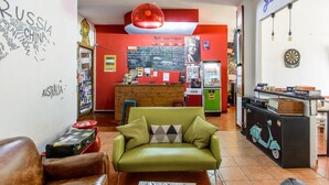 Eine gemütliche Hotelhalle mit einem grünen Sofa, einem Holzbüro und einer Dartscheibe an der Wand.