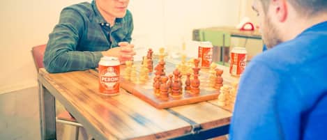Dos personas jugando ajedrez en una mesa de madera con una lata de cerveza Peroni.