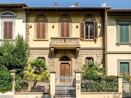 Un edificio de dos pisos con entrada central, fachada de piedra y contraventanas en las ventanas.