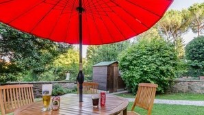A wooden table with four chairs, a red umbrella, and two glasses of beer. - Sangaggio House B&B (Florence)