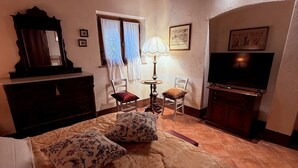 A bedroom with a bed, dresser, TV, and a window with curtains. - Il Pettirosso di Siena (Siena)