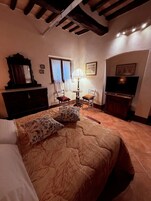 Una camera da letto con un letto, una cassettiera, una televisione e una finestra con tende.