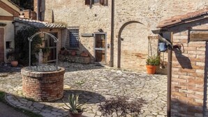 A stone building with a courtyard, a metal water fountain, and potted plants. - Il Pettirosso di Siena (Siena)