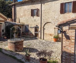 Un edificio in pietra con un cortile interno, una fontana in metallo e piante in vaso.