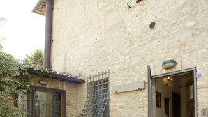 A stone-paved courtyard with potted plants and a wooden door. - Il Pettirosso di Siena (Siena)