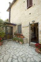 Un cortile lastricato in pietra con piante in vaso e una porta in legno.