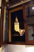 A window with a view of a brightly lit tower at night.